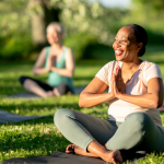 The sun shines on a woman sitting on her yoga mat as she takes part in her senior yoga class.