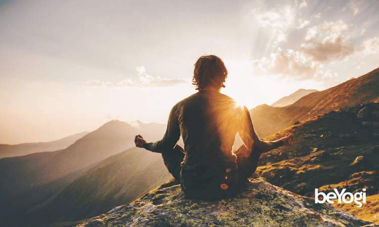 A yogi mediates on a mountaintop as his aura glows yellow.