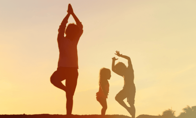 A kids yoga teacher instructs a kids yoga class in the sunset.