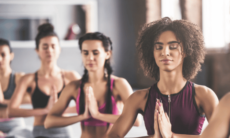 A yoga class runs through a prepared yoga sequence.