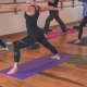 A hot yoga class works through a hot yoga sequence.