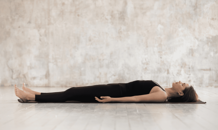A yogi does corpse pose in her Halloween yoga sequence.