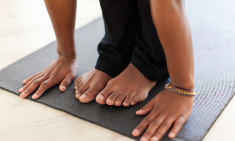 A barefoot yogi instructor teaches yoga to her yoga class.