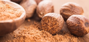 Ground nutmeg spice in the wooden spoon closeup